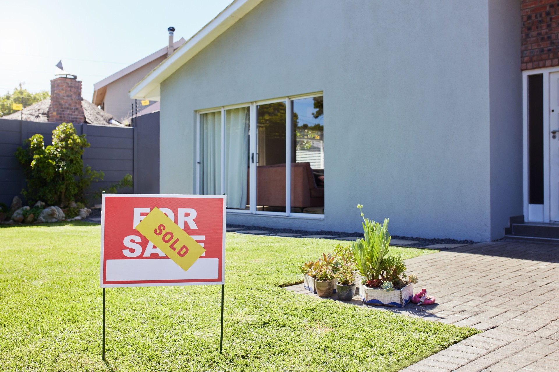 Sold For Sale sign on lawn of modern suburban house